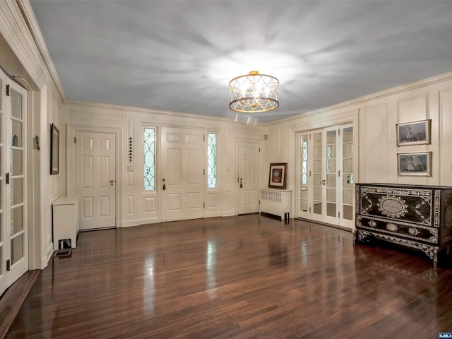 foyer entrance featuring ornamental molding, an inviting chandelier, radiator, and dark wood-type flooring