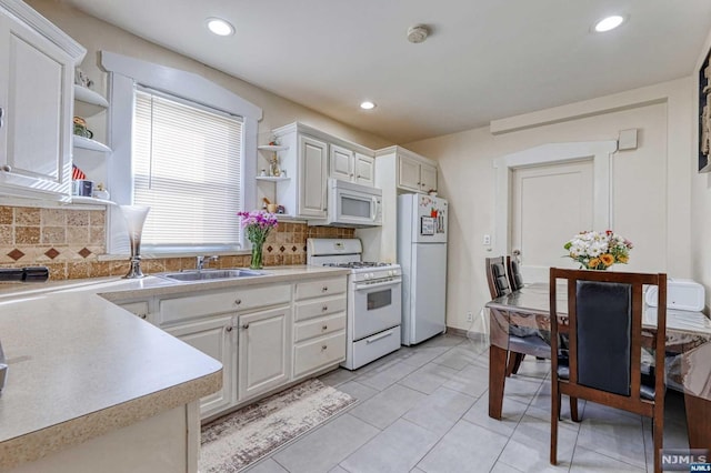 kitchen featuring white cabinetry, sink, white appliances, decorative backsplash, and light tile patterned floors