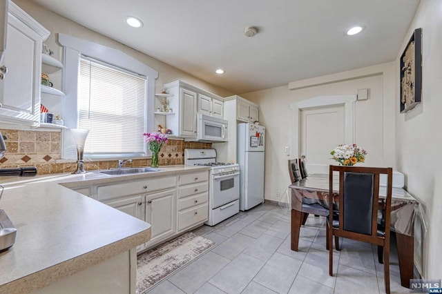 kitchen featuring tasteful backsplash, sink, white cabinets, and white appliances