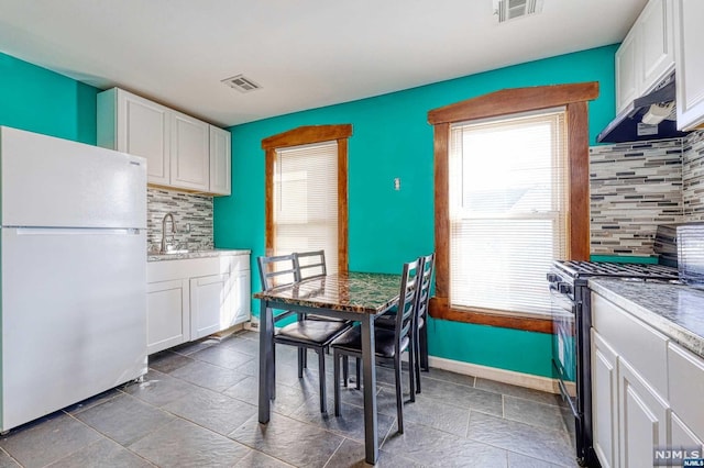 kitchen featuring black gas range, backsplash, exhaust hood, white fridge, and white cabinetry