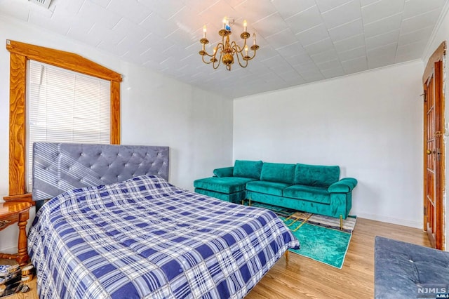 bedroom with wood-type flooring and a notable chandelier