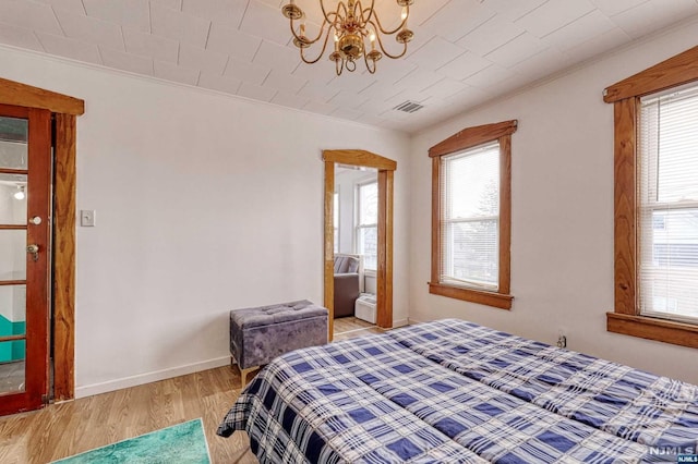 bedroom featuring light hardwood / wood-style flooring, a notable chandelier, and ornamental molding