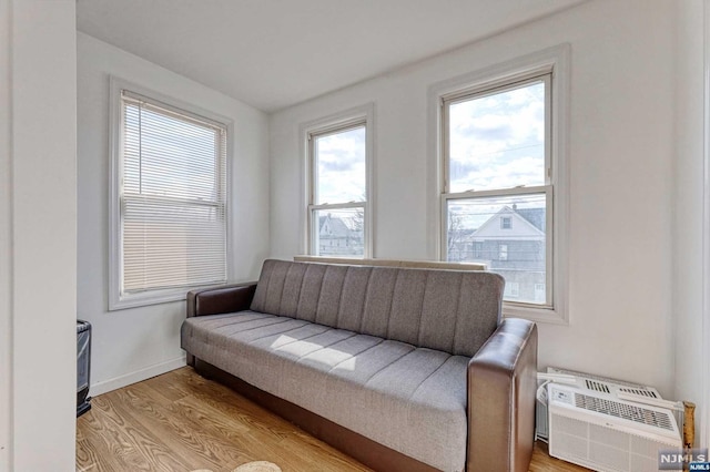 sitting room featuring light wood-type flooring and an AC wall unit