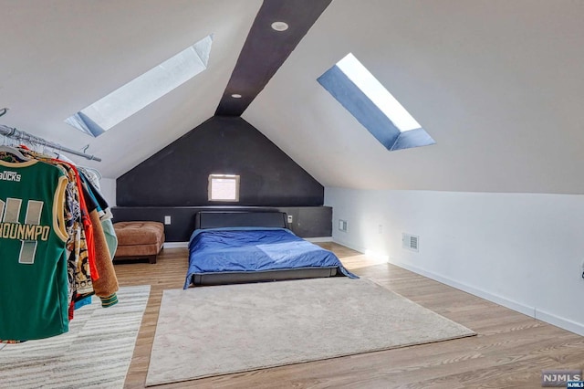 bedroom with lofted ceiling with skylight and light hardwood / wood-style floors