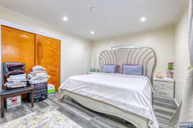 bedroom featuring hardwood / wood-style floors, a closet, and crown molding