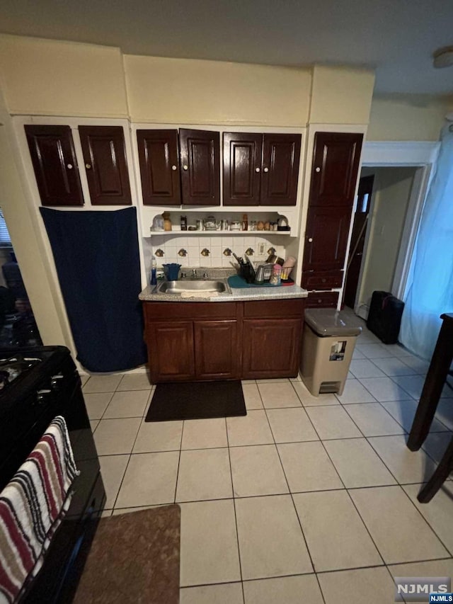 kitchen featuring light tile patterned flooring, decorative backsplash, dark brown cabinets, and sink