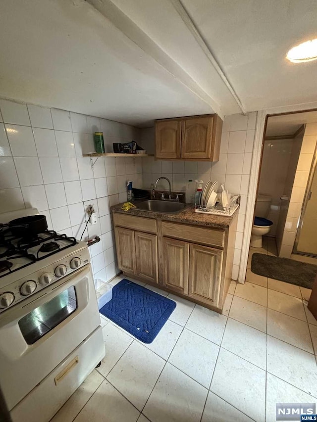 kitchen featuring sink, light tile patterned floors, tile walls, tasteful backsplash, and white range with gas cooktop