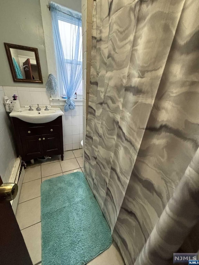 bathroom featuring tile patterned flooring, vanity, tile walls, and a baseboard radiator