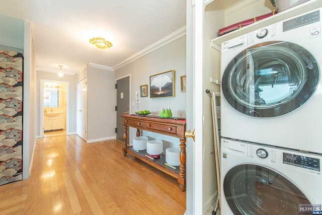 laundry area featuring light hardwood / wood-style floors, ornamental molding, and stacked washer / dryer