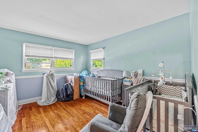 bedroom with hardwood / wood-style floors and a crib