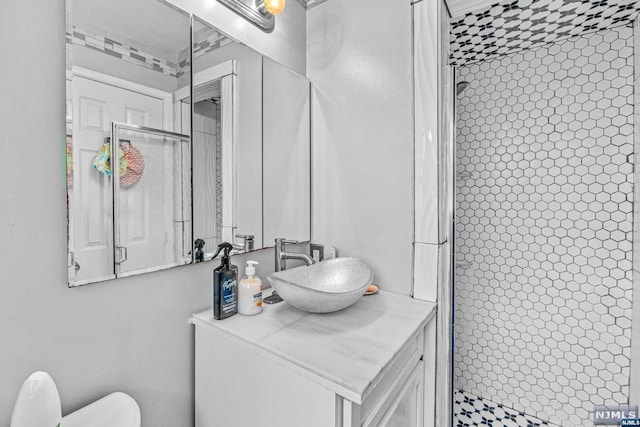 bathroom with tiled shower, vanity, and toilet