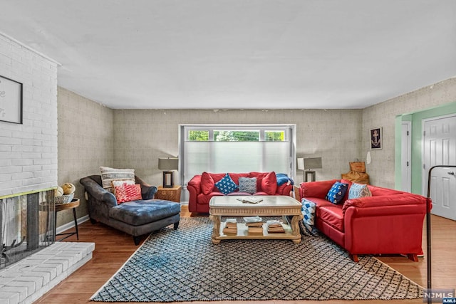 living room featuring wood-type flooring and a brick fireplace