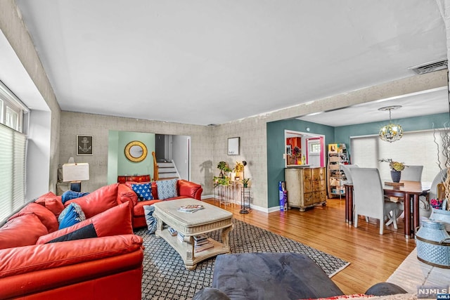 living room with wood-type flooring, a wealth of natural light, and an inviting chandelier