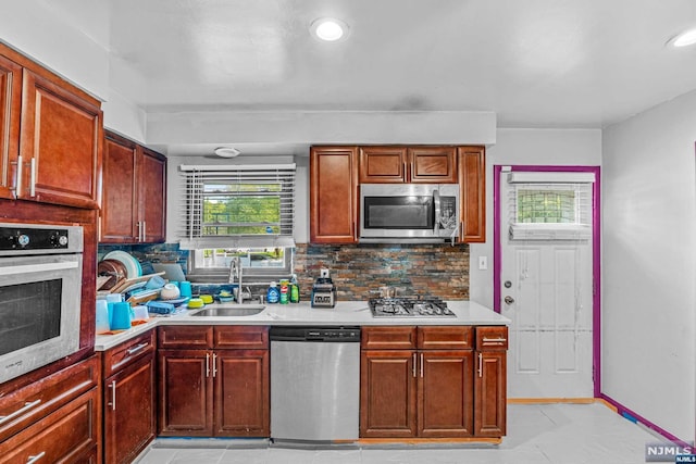 kitchen with appliances with stainless steel finishes, backsplash, light tile patterned floors, and sink