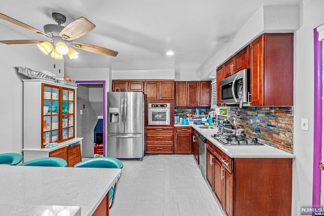 kitchen featuring decorative backsplash, appliances with stainless steel finishes, ceiling fan, and sink