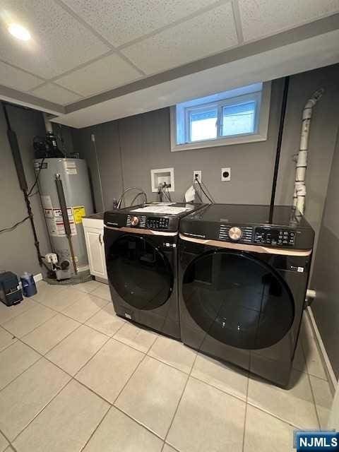 washroom with washer and clothes dryer, light tile patterned floors, and water heater