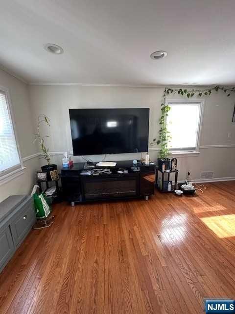 living room featuring wood-type flooring and ornamental molding