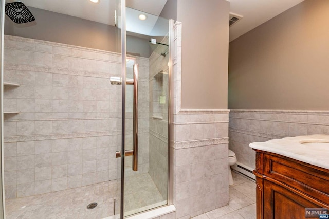 bathroom with tile patterned flooring, toilet, tile walls, and a baseboard heating unit