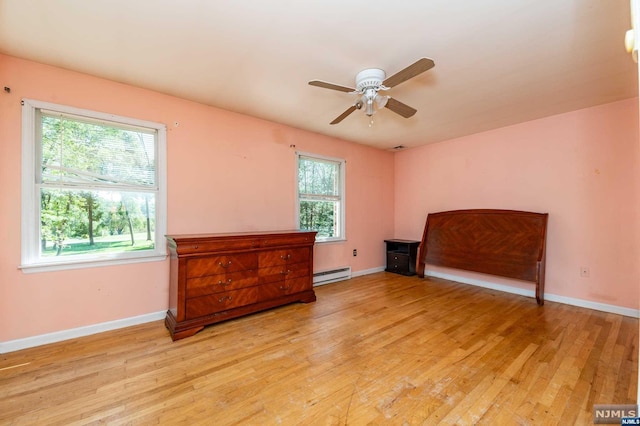 interior space featuring baseboard heating, light hardwood / wood-style flooring, multiple windows, and ceiling fan