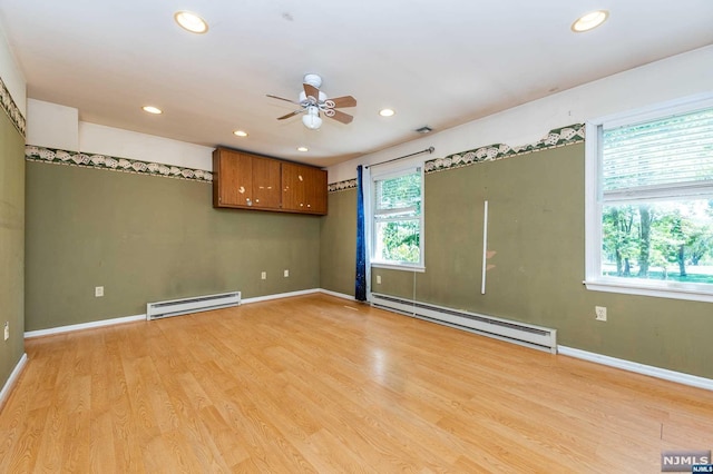 unfurnished room featuring light hardwood / wood-style floors, plenty of natural light, and baseboard heating