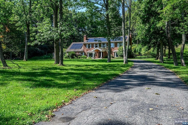 view of front of home with a front yard and solar panels