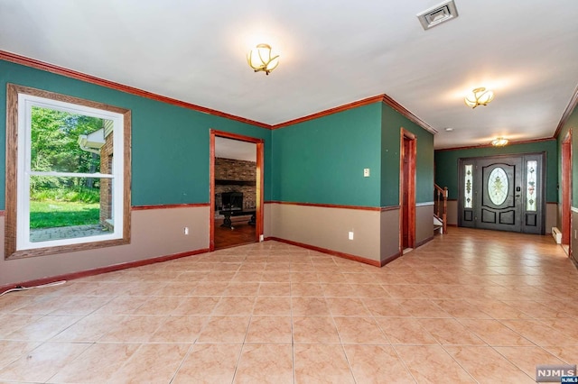 spare room featuring a fireplace, light tile patterned floors, and crown molding