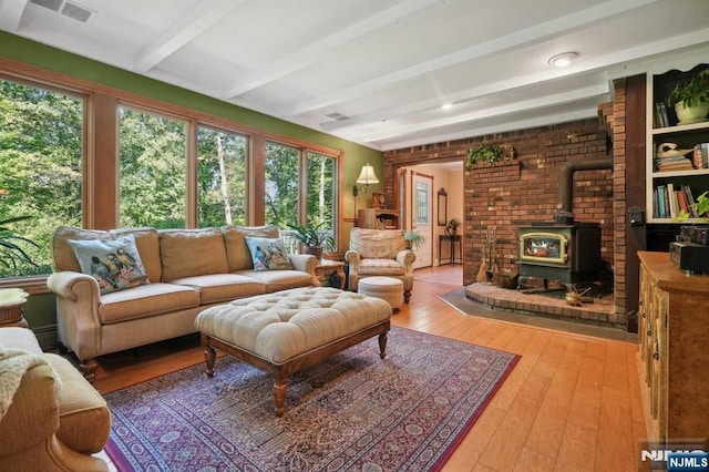 sunroom / solarium featuring beamed ceiling and a wood stove