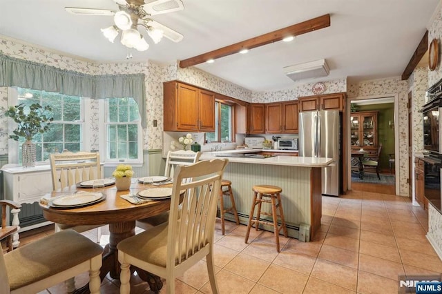 kitchen with beam ceiling, light tile patterned flooring, stainless steel refrigerator, and a healthy amount of sunlight