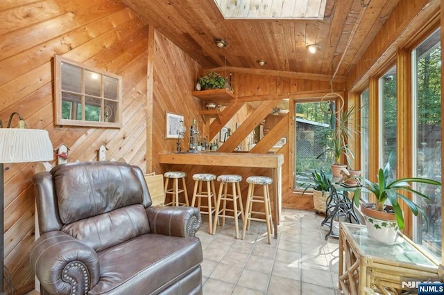 living area featuring wooden walls, lofted ceiling, wood ceiling, and a healthy amount of sunlight