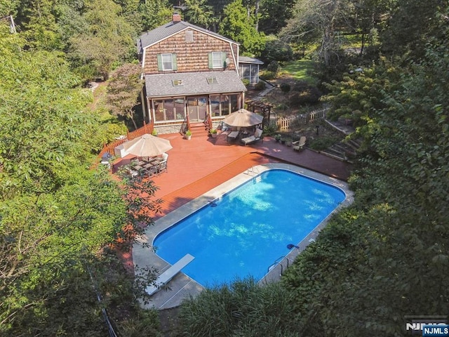 view of pool featuring a deck and a sunroom