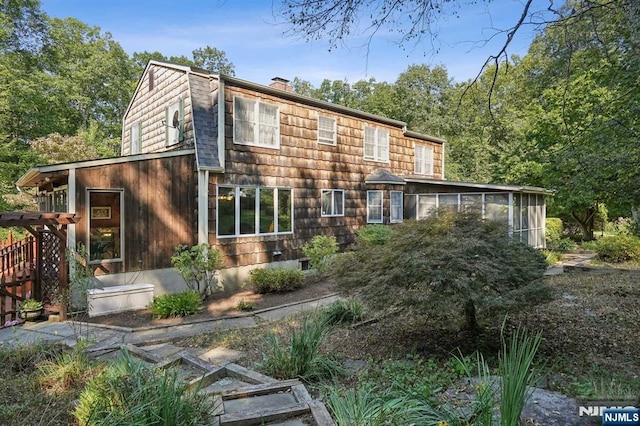 rear view of property featuring a sunroom