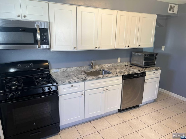 kitchen with white cabinets, appliances with stainless steel finishes, light tile patterned floors, and sink