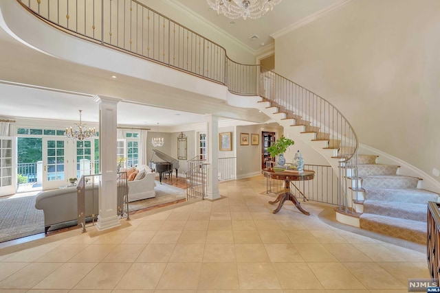 staircase with ornate columns, french doors, a high ceiling, crown molding, and a chandelier