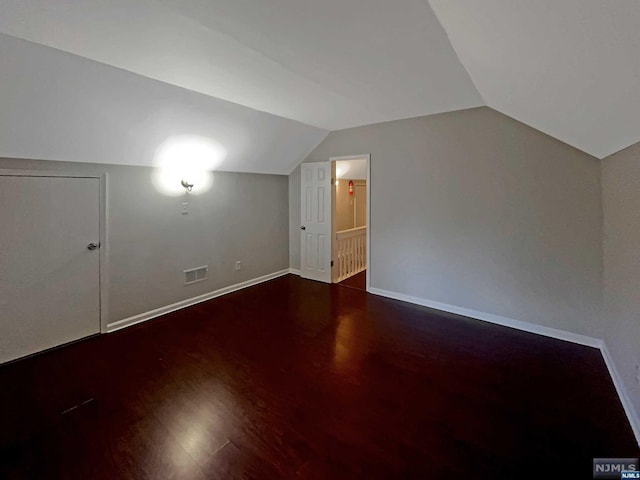 additional living space with hardwood / wood-style floors and vaulted ceiling