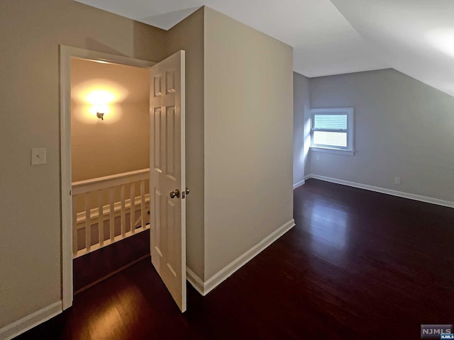 additional living space with dark wood-type flooring and vaulted ceiling