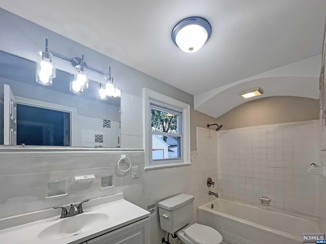 full bathroom featuring tile walls, vanity, tiled shower / bath combo, and toilet