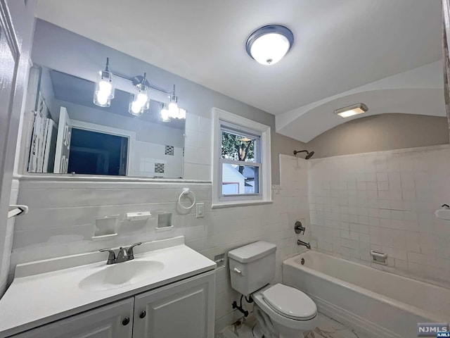 full bathroom featuring tile walls, vanity, tiled shower / bath combo, and toilet