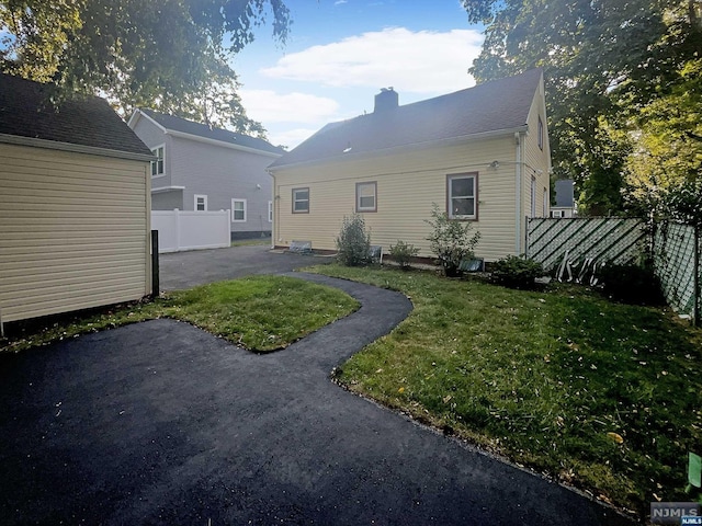 back of house with a patio and a lawn