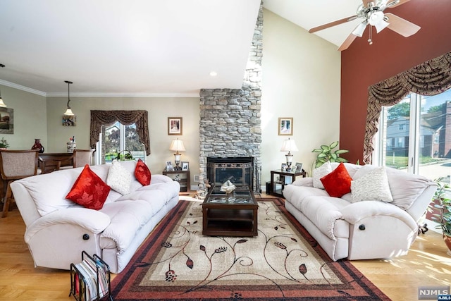 living room featuring a fireplace, light wood-type flooring, vaulted ceiling, and ornamental molding