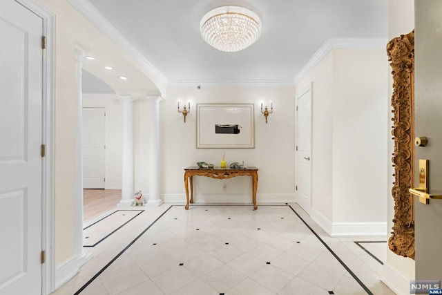 hallway with a chandelier, decorative columns, and ornamental molding