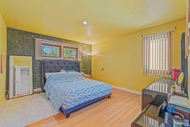 bedroom with baseboard heating, multiple windows, and hardwood / wood-style floors