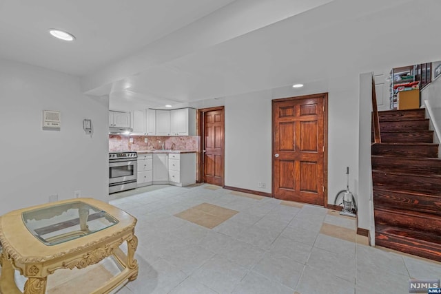 kitchen featuring stainless steel range with electric stovetop, white cabinets, light tile patterned floors, and tasteful backsplash