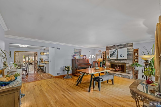 dining room featuring light hardwood / wood-style floors, ornamental molding, and a fireplace