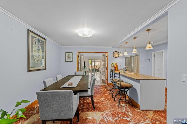 dining space featuring sink, crown molding, and french doors