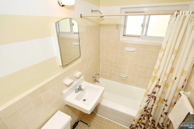 bathroom featuring shower / tub combo, tile walls, and sink