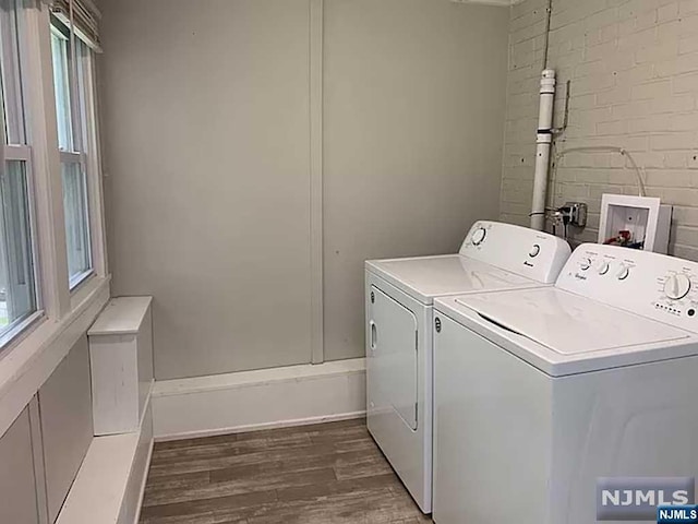 laundry room featuring washer and dryer, dark hardwood / wood-style floors, and brick wall