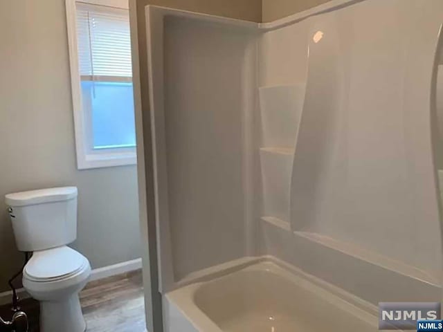 bathroom with hardwood / wood-style floors, shower / bath combination, and toilet