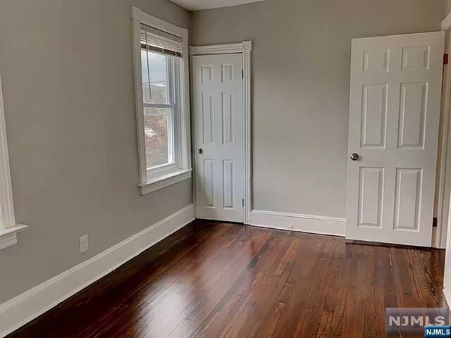 unfurnished bedroom with dark wood-type flooring