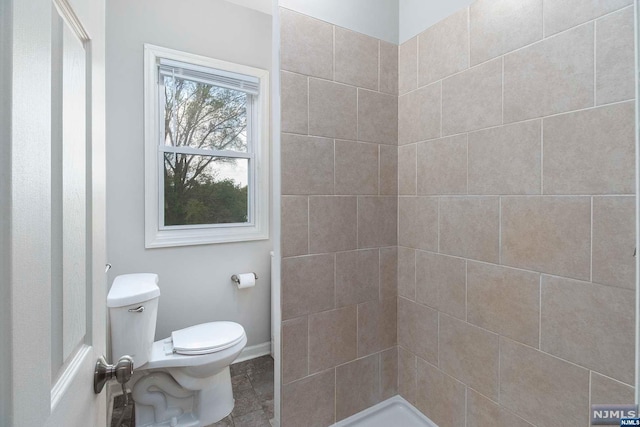 bathroom with a tile shower and toilet