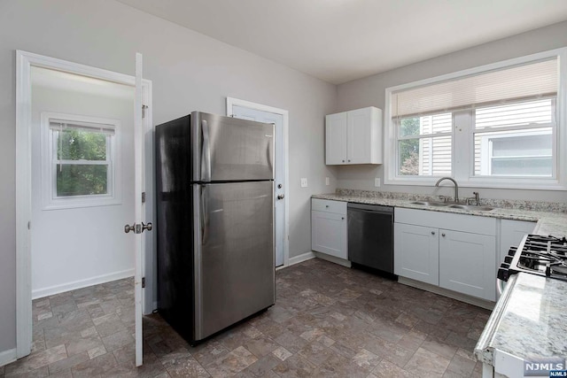 kitchen with white cabinets, light stone counters, sink, and appliances with stainless steel finishes